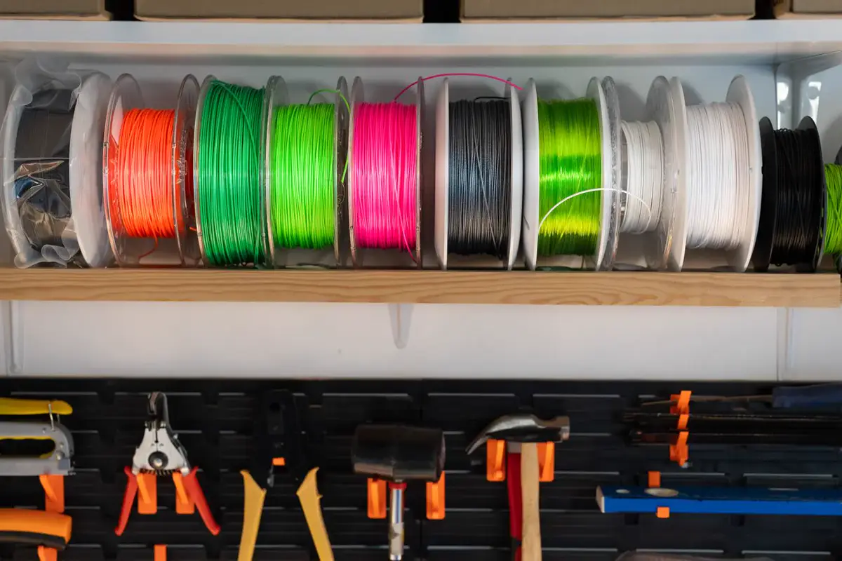 Des bobines de filament de plusieurs couleurs rangées sur une étagère