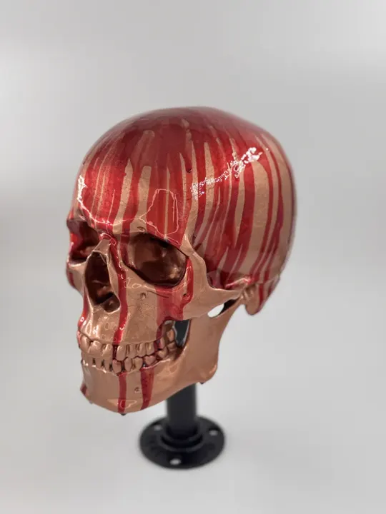 Crâne décoratif imprimé en 3D, peint en rouge brillant avec des coulures, sur un pied noir