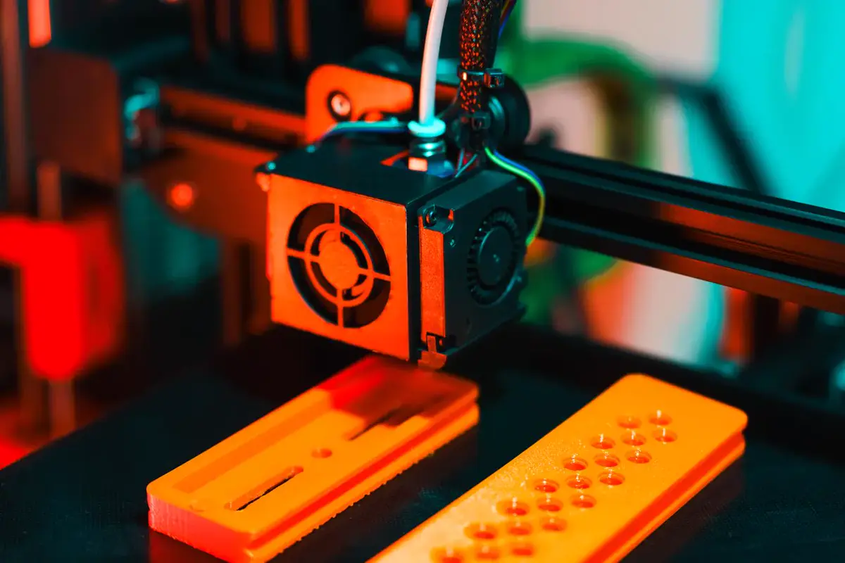 Gros plan sur une imprimante 3D en train de déposer du plastique orange