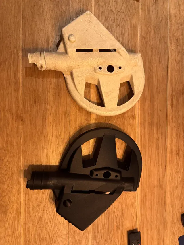 Une pièce d'origine cassée, claire, posée au-dessus de sa copie noire imprimée en 3D